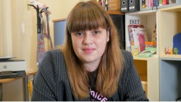 Woman with long light brown hair with bangs wearing a pinstripe grey blazer